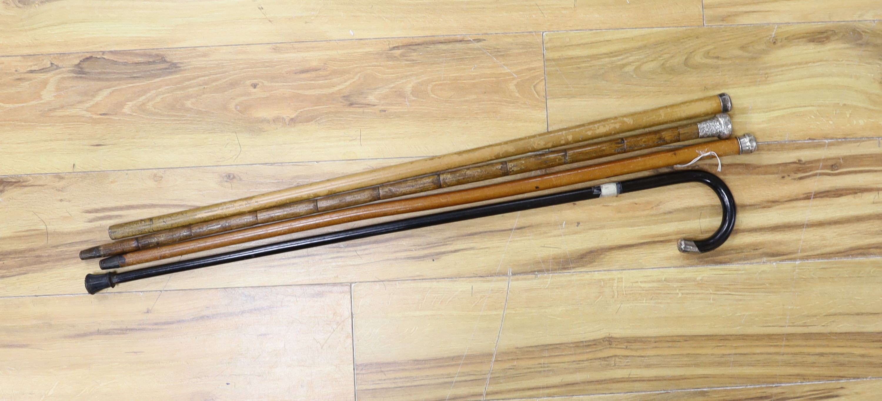 Four silver topped walking canes, longest 85 cms high.